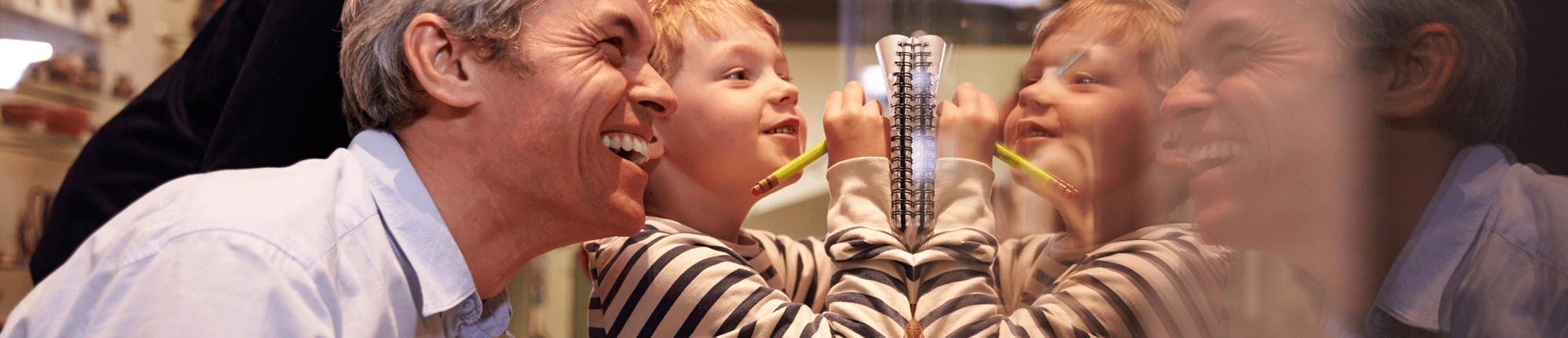Smiling man and young boy drawing together on a glass surface, their reflections visible, creating a joyful and mirrored scene Smiling man and young boy drawing together on a glass surface, their reflections visible, creating a joyful and mirrored scene