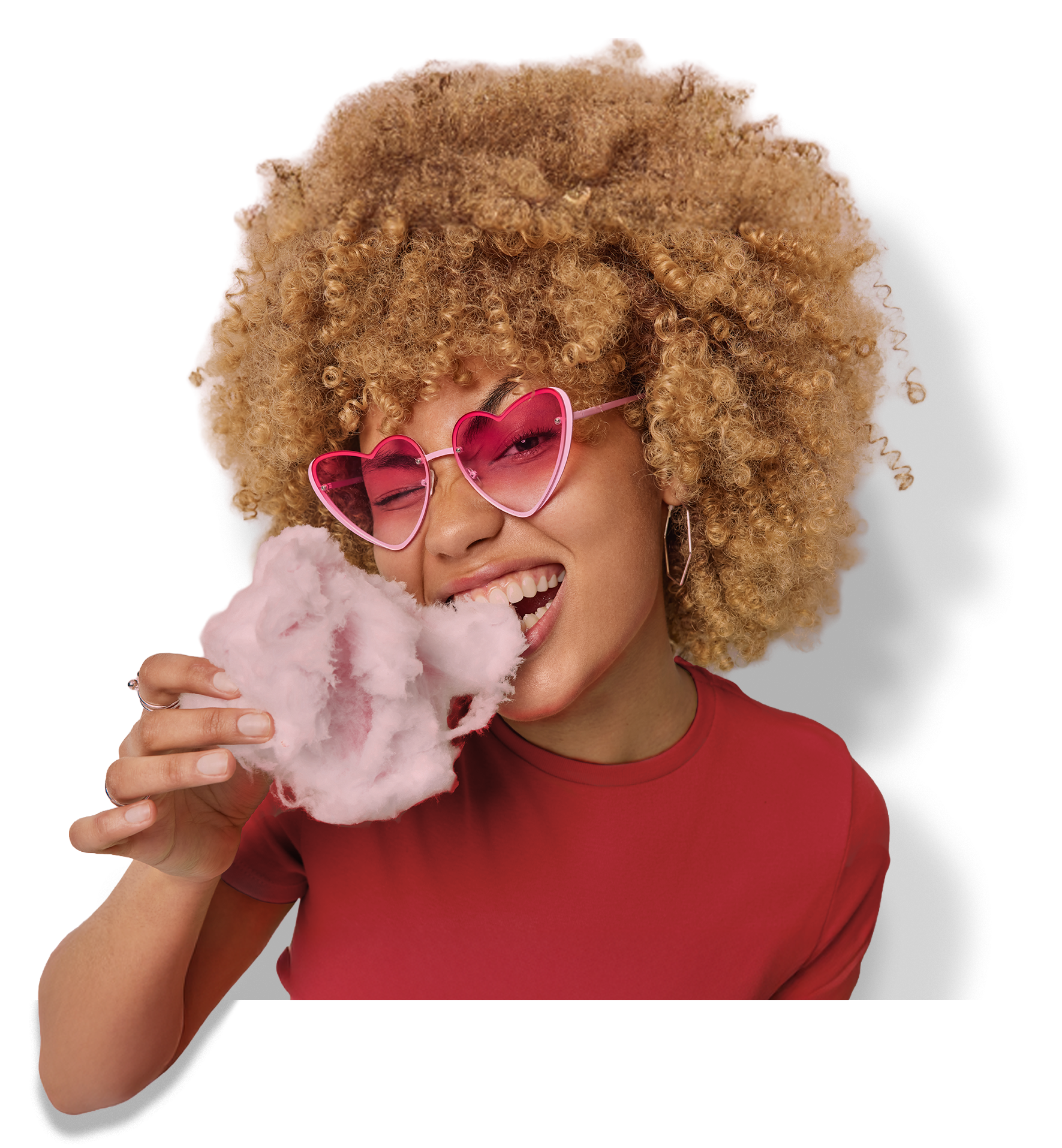 Girl wearing heart shaped sunglasses taking a bite out of candy floss